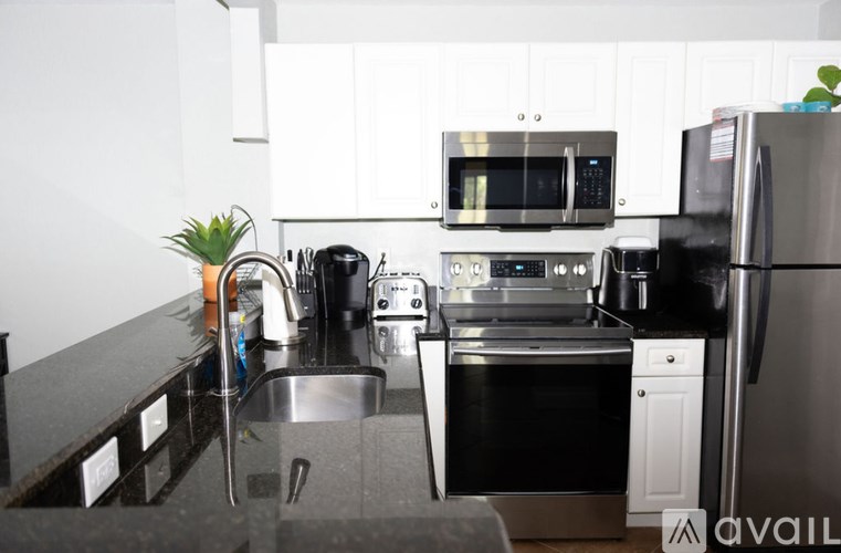 A kitchen with a black countertop and stainless steel appliances.