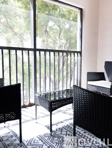 A balcony with a table and chairs overlooking a tree-filled yard.