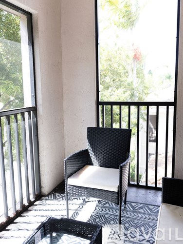 A black chair and a black table are on a balcony.