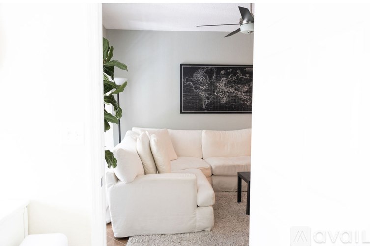 A white couch with a black and white painting on the wall behind it.