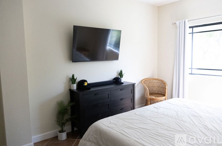 A bedroom with a bed, chair, and a flat screen TV mounted on the wall.