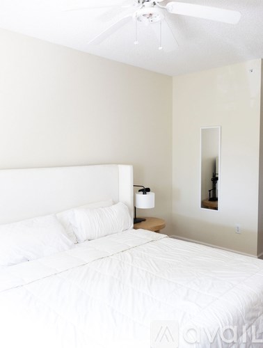A white bed with a white pillow and a white bedspread.