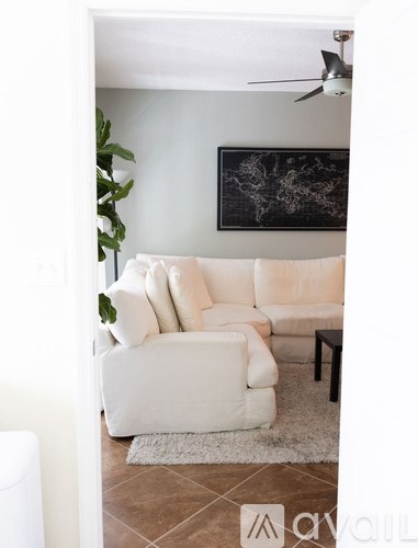 A living room with a white couch and a ceiling fan.