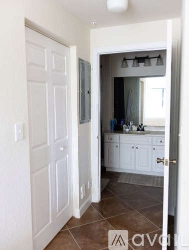 A bathroom with a white door and brown tiles.