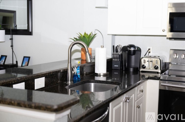 A modern kitchen with a black countertop and stainless steel appliances.
