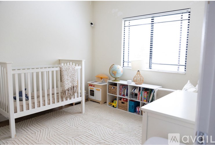 A white crib sits next to a window in a nursery.