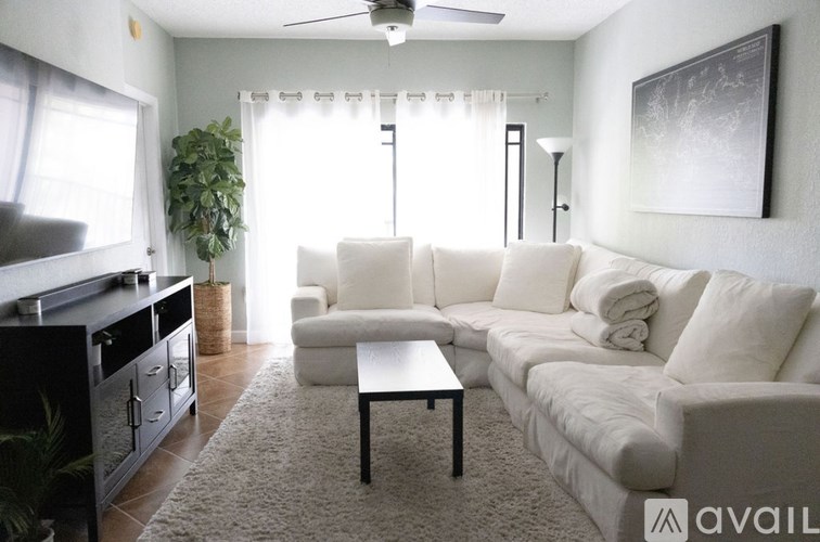 A living room with a white couch, a coffee table, and a ceiling fan.