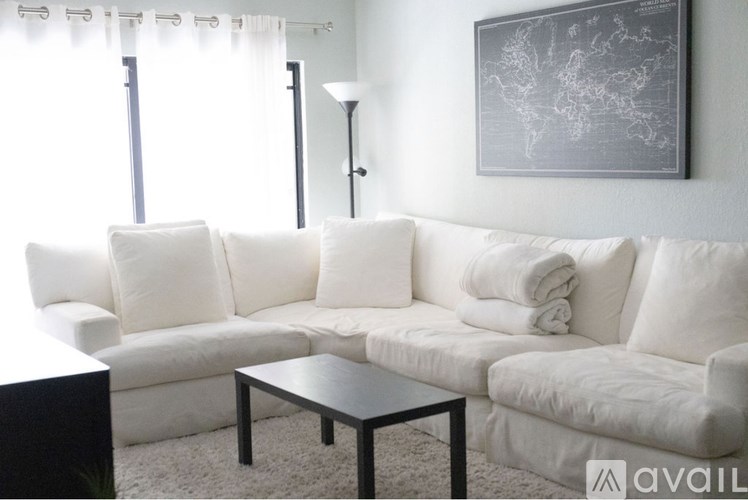 A white couch with a black coffee table in front of it.