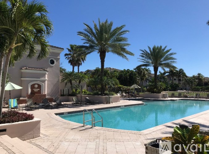 A pool surrounded by palm trees and a white building.