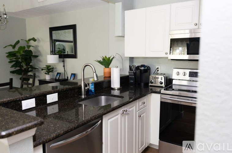 A kitchen with white cabinets and a black counter top.