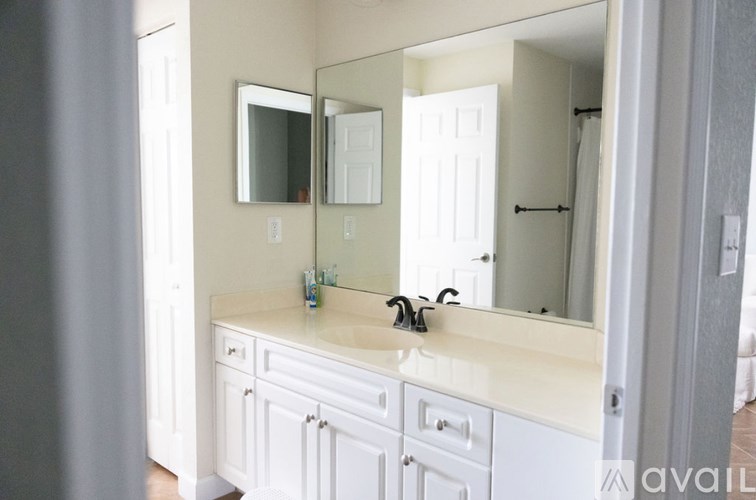 A bathroom with a sink, mirror, and cabinets.