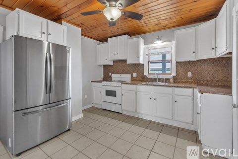 A kitchen with a stainless steel refrigerator and white cabinets.