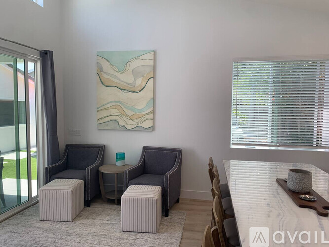 A living room with a grey sofa, ottoman, and a painting on the wall.