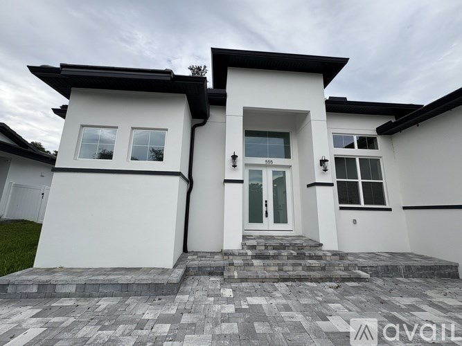 A modern white house with a black roof and a glass door.