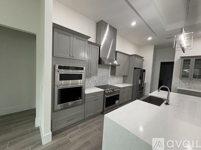 A modern kitchen with stainless steel appliances and a marble countertop.