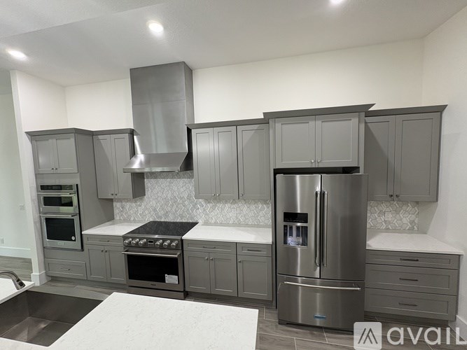 A modern kitchen with a stainless steel refrigerator and oven.