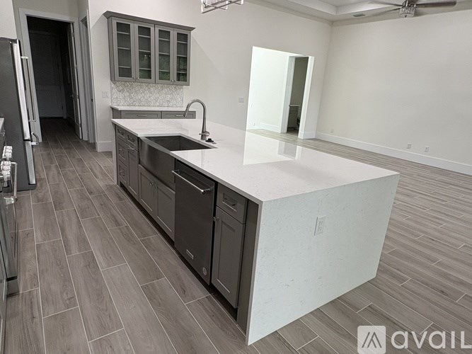 A kitchen with a white countertop and dark wood flooring.