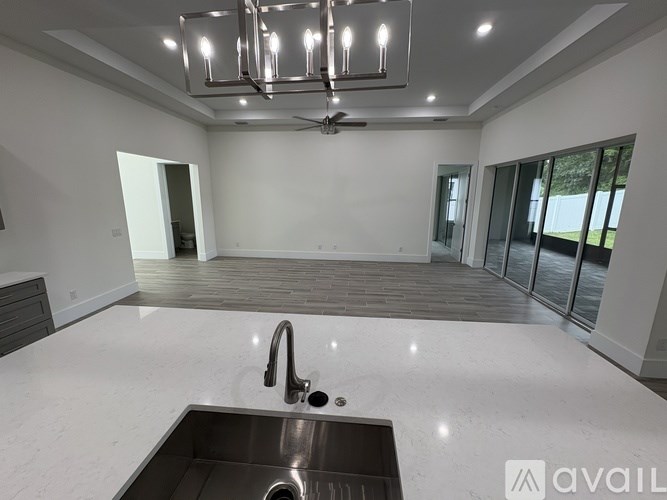 A modern kitchen with a stainless steel sink and a ceiling fan.