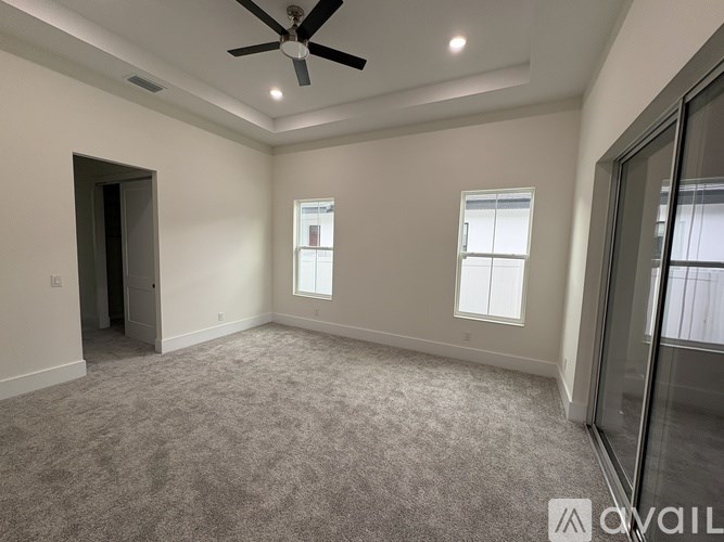 A spacious room with a ceiling fan and two windows.