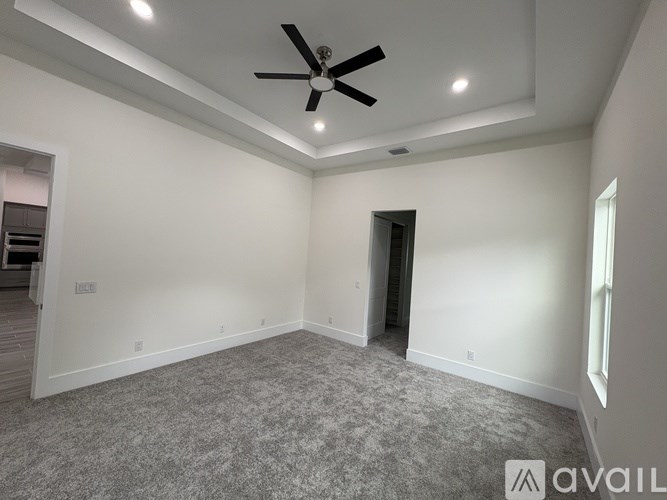 A spacious room with a ceiling fan and carpeted floor.
