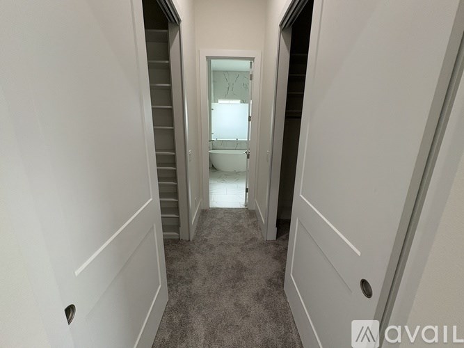 A hallway with a carpeted floor and a staircase leading to a bathroom.