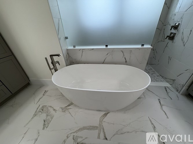 A white bathtub sits in a marble bathroom.