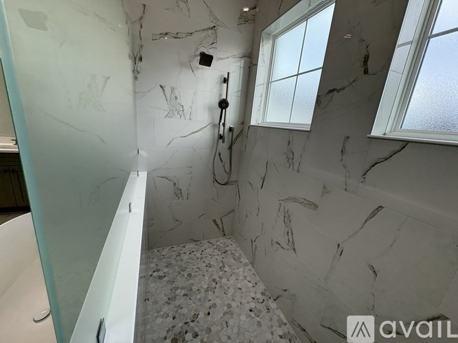 A bathroom with marble walls and a shower area.