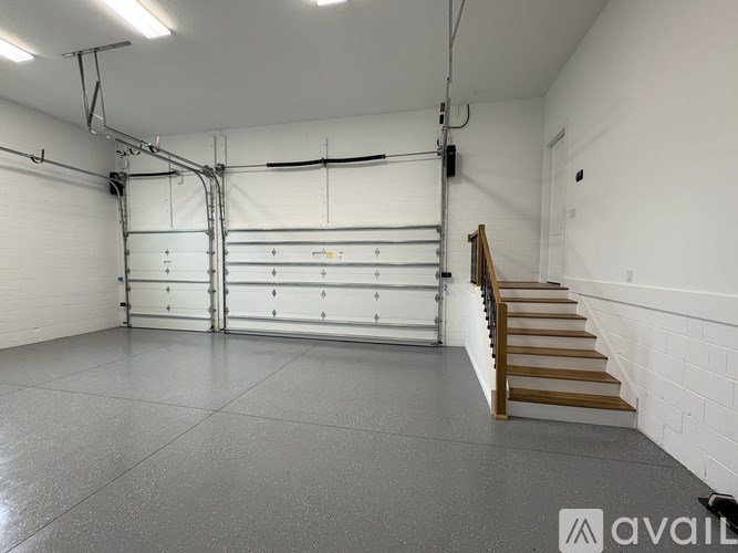 A spacious garage with a staircase leading to the upper level.