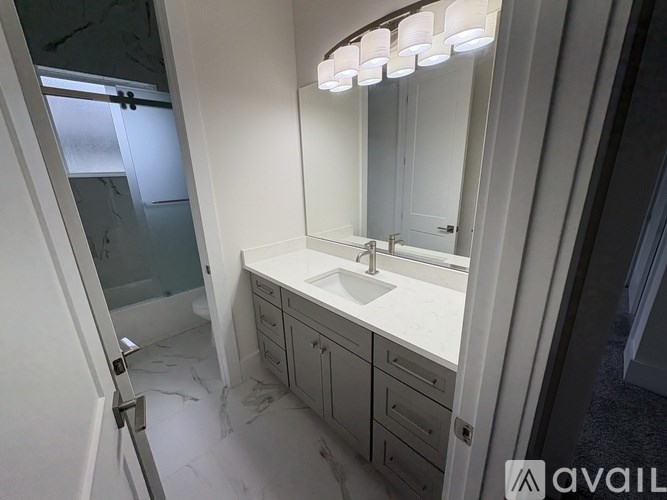 A bathroom with a sink, mirror, and a glass shower door.