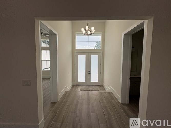 A room with a wooden floor and a chandelier hanging from the ceiling.