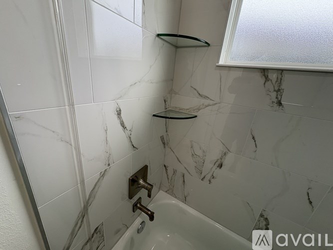 A bathroom with a marble tile wall and a round shower head.