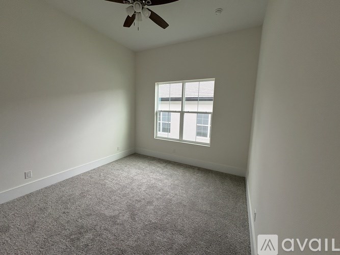 A room with a ceiling fan and a window with blinds.