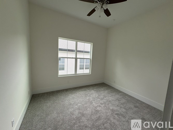 A room with a ceiling fan and a window with blinds.