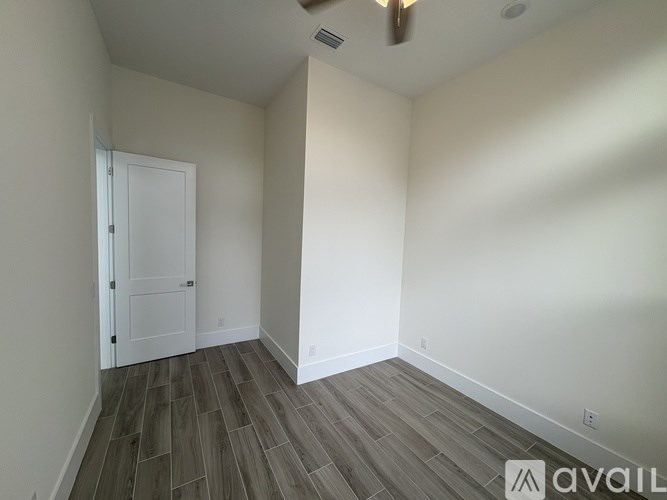 A room with a white door and wooden flooring.