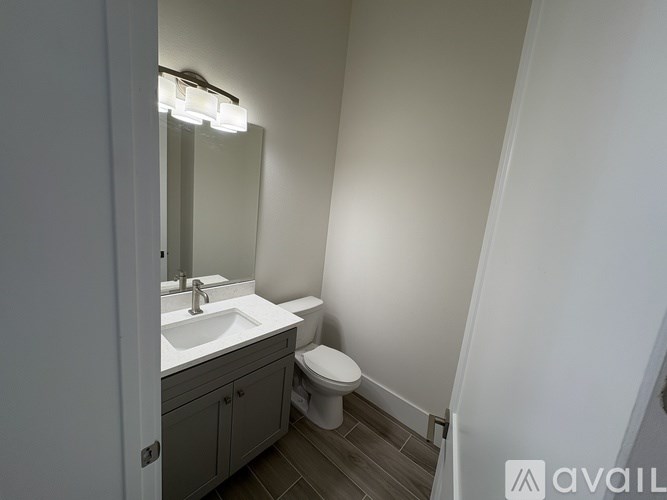 A bathroom with a toilet, sink, and mirror.