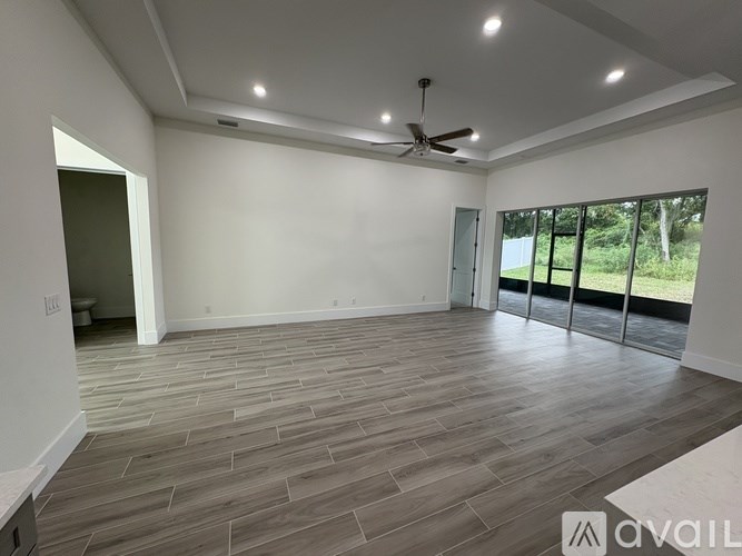 A spacious room with a ceiling fan and sliding glass doors.