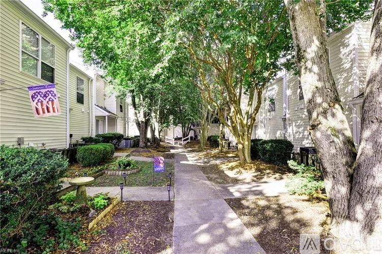 A tree-lined walkway leads to a building with a flag hanging from the window.