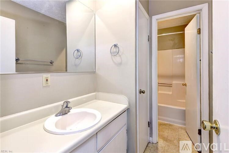 A bathroom with a sink, mirror, and bathtub.