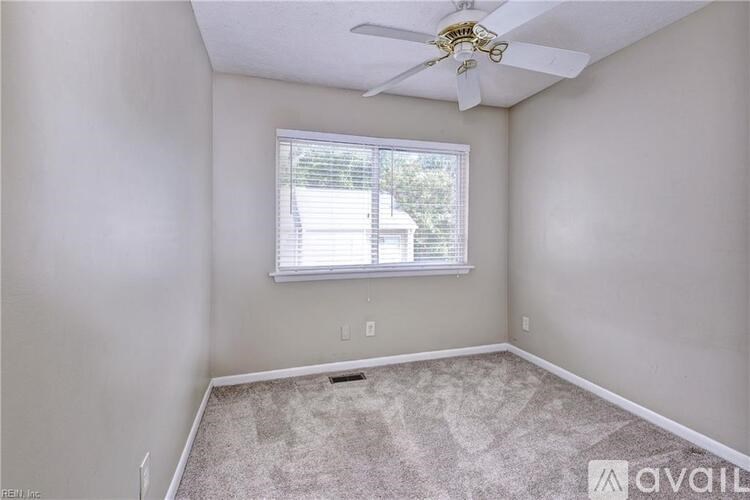 A room with a ceiling fan and a window with blinds.