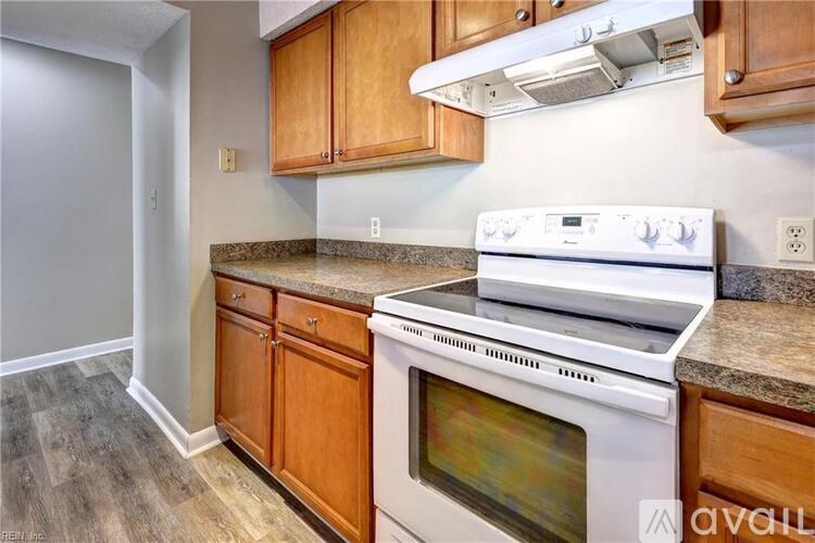 A kitchen with a white stove top oven and wooden cabinets.