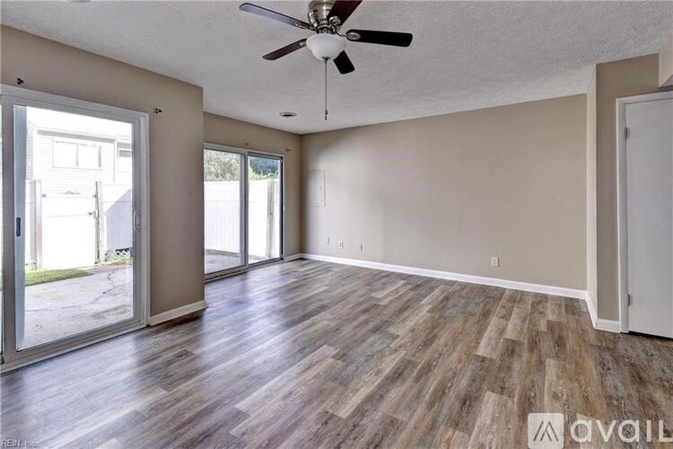A room with a ceiling fan and sliding glass doors.