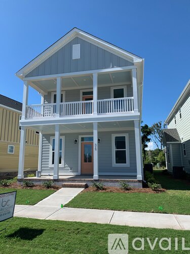 A two-story house with a balcony and a sign in front.
