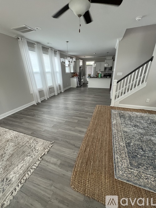 A spacious room with a fan and a staircase.