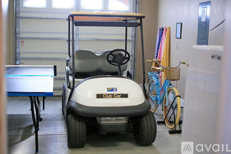 A white golf cart with the words "Club Car" on the front is parked in a garage.