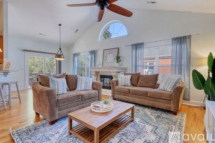 A living room with a brown couch, a coffee table, and a ceiling fan.