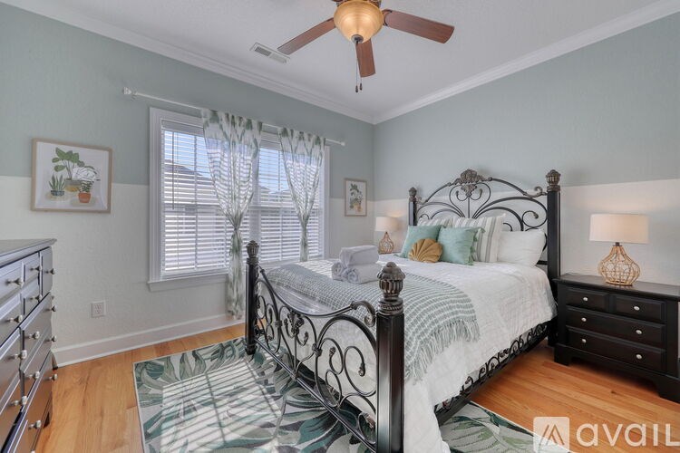 A bedroom with a bed, dresser, and window with curtains.