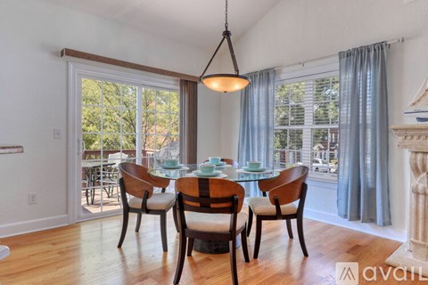 A dining room with a table set for four and a view of the backyard.