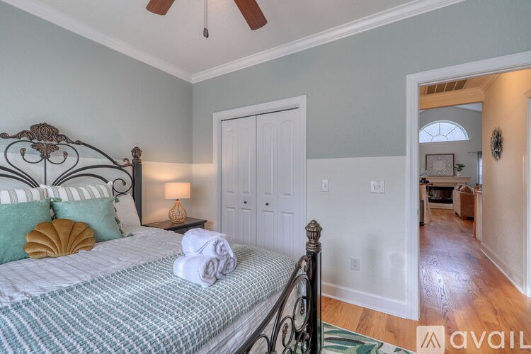 A bedroom with a bed, pillows, a lamp, and a ceiling fan.
