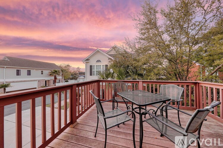 A deck with a table and chairs overlooking a residential area.