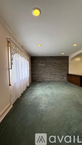 A room with a carpeted floor and a brick wall.